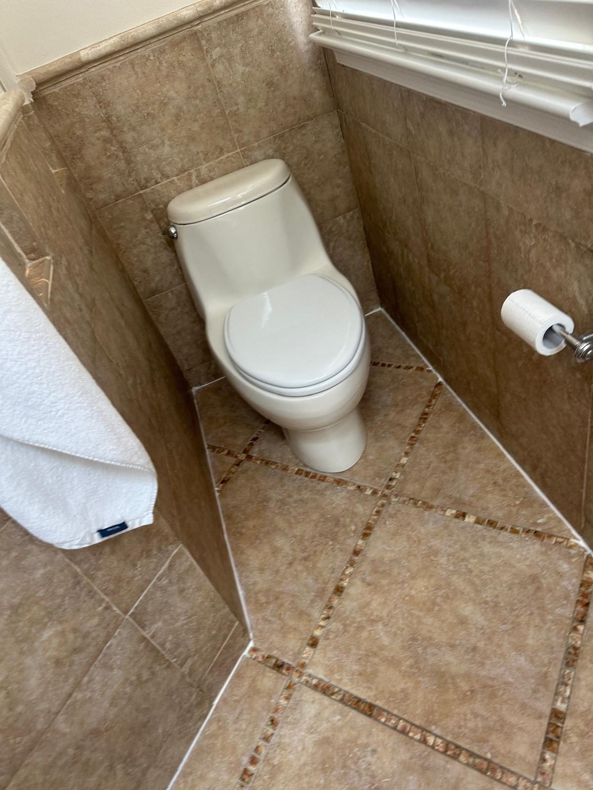 Fresh white caulk bead along the joint where tiled walls meet the tiled floor