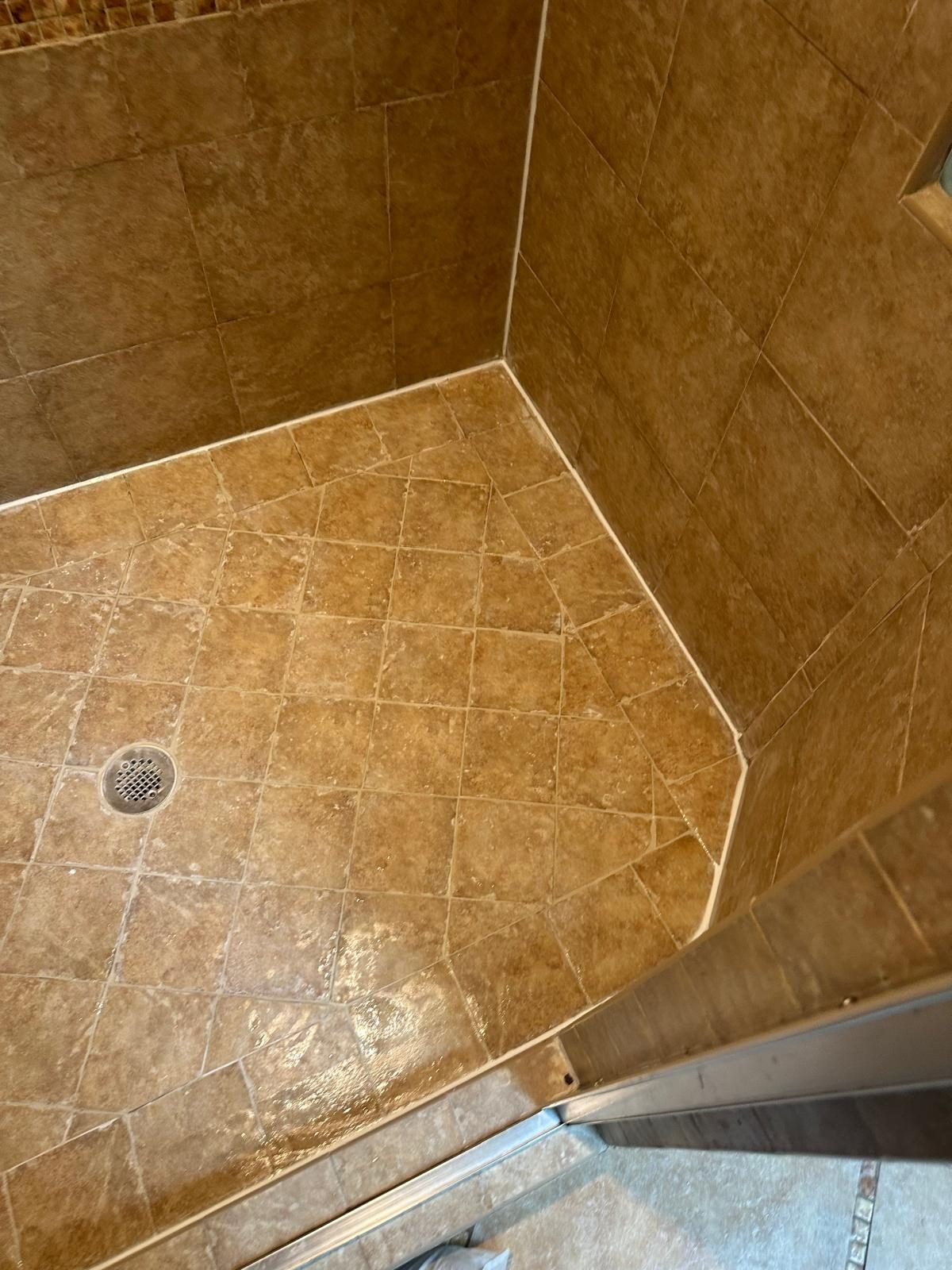 Tiled shower pan with discolored grout lines and stained corner joints