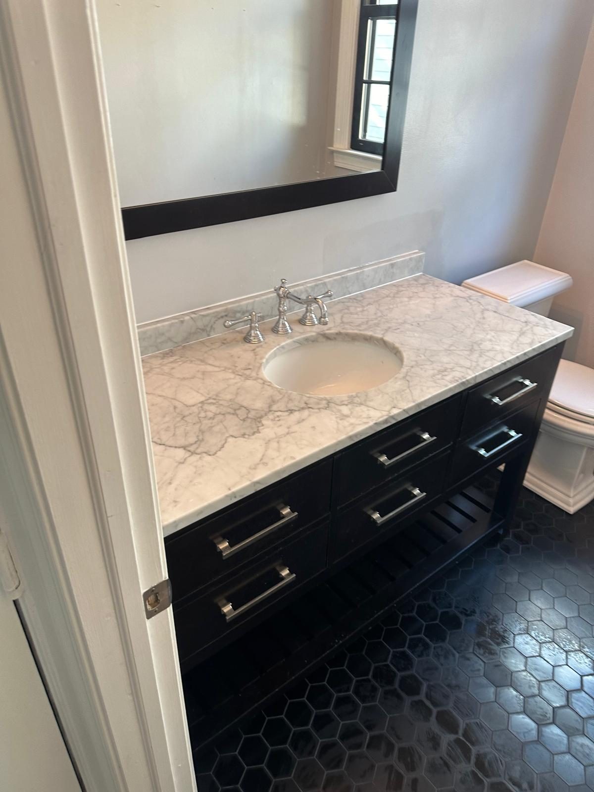 New dark vanity with marble countertop and framed mirror above