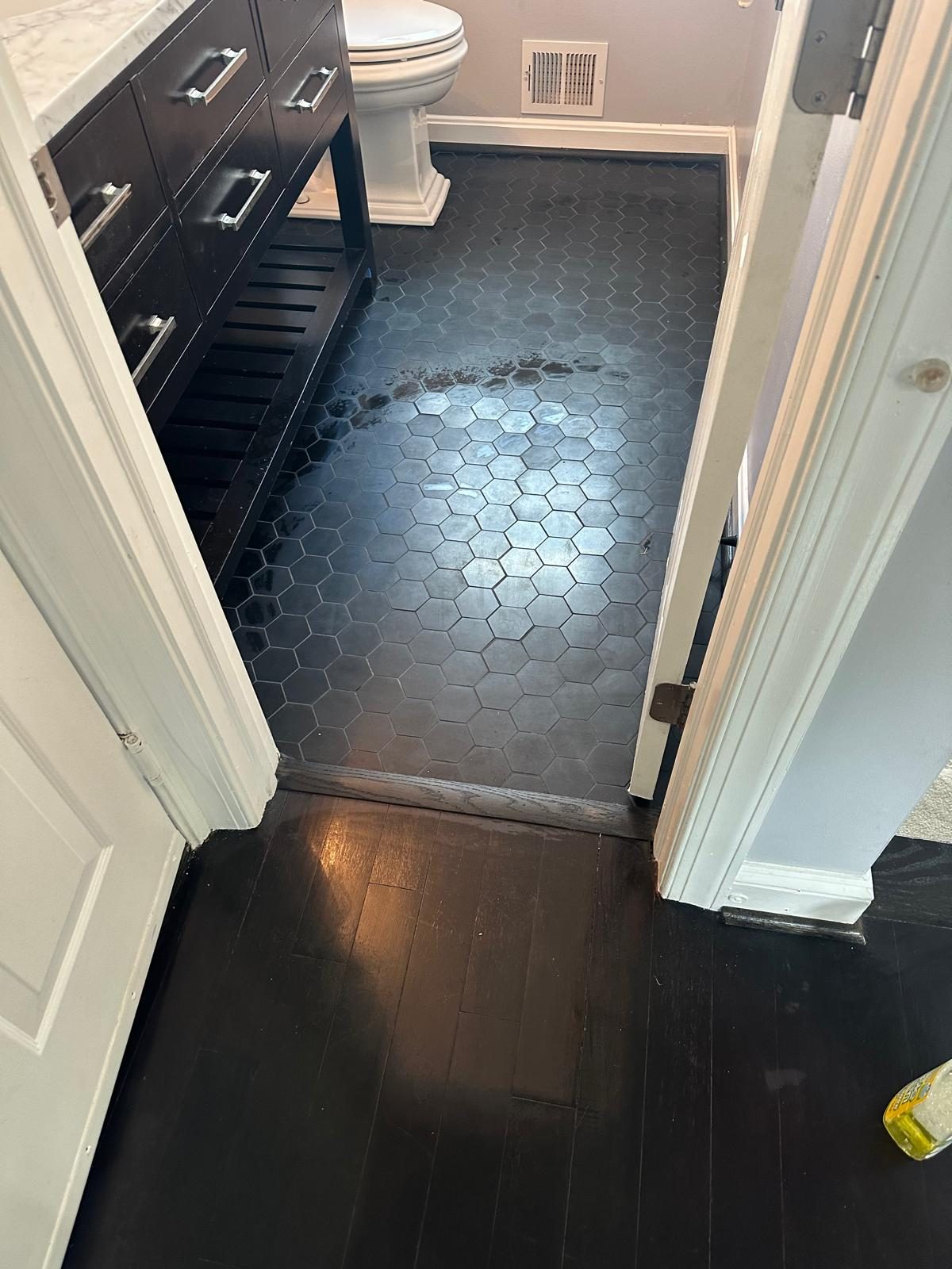 The same powder room from the doorway after work, with black hexagon tile flooring