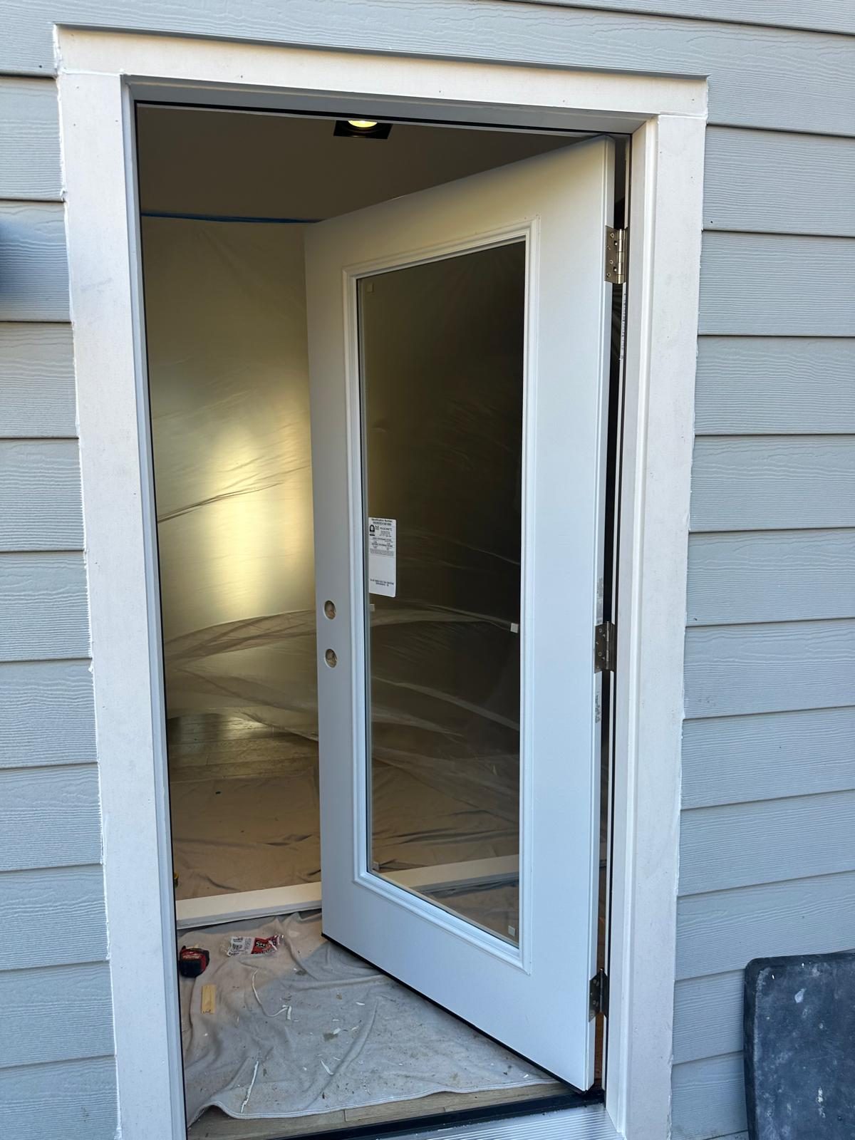 New white full-lite exterior door hung and trimmed in its opening, standing open