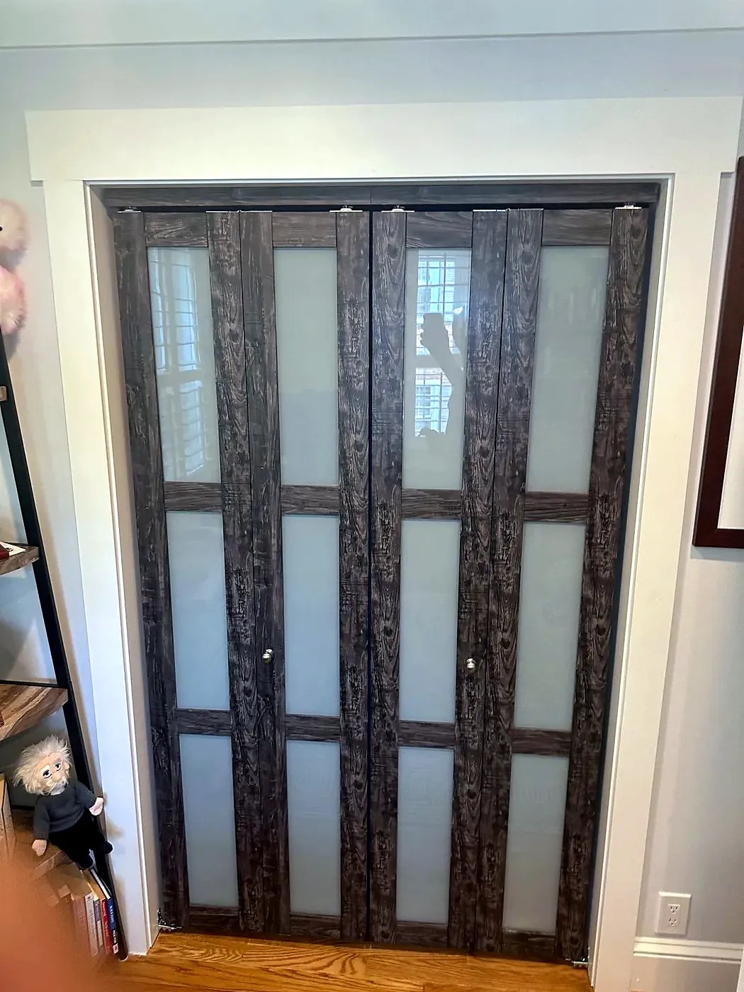 Dark wood bifold closet doors with frosted glass panels installed in a white-trimmed opening