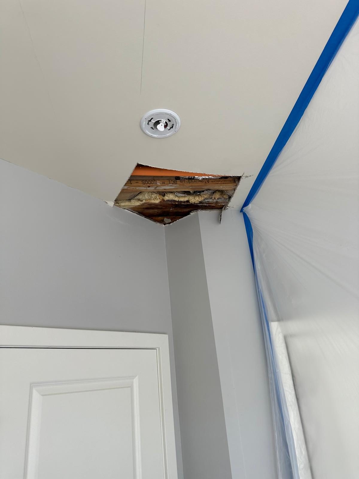 Ceiling drywall cut open at a corner exposing a joist and insulation above