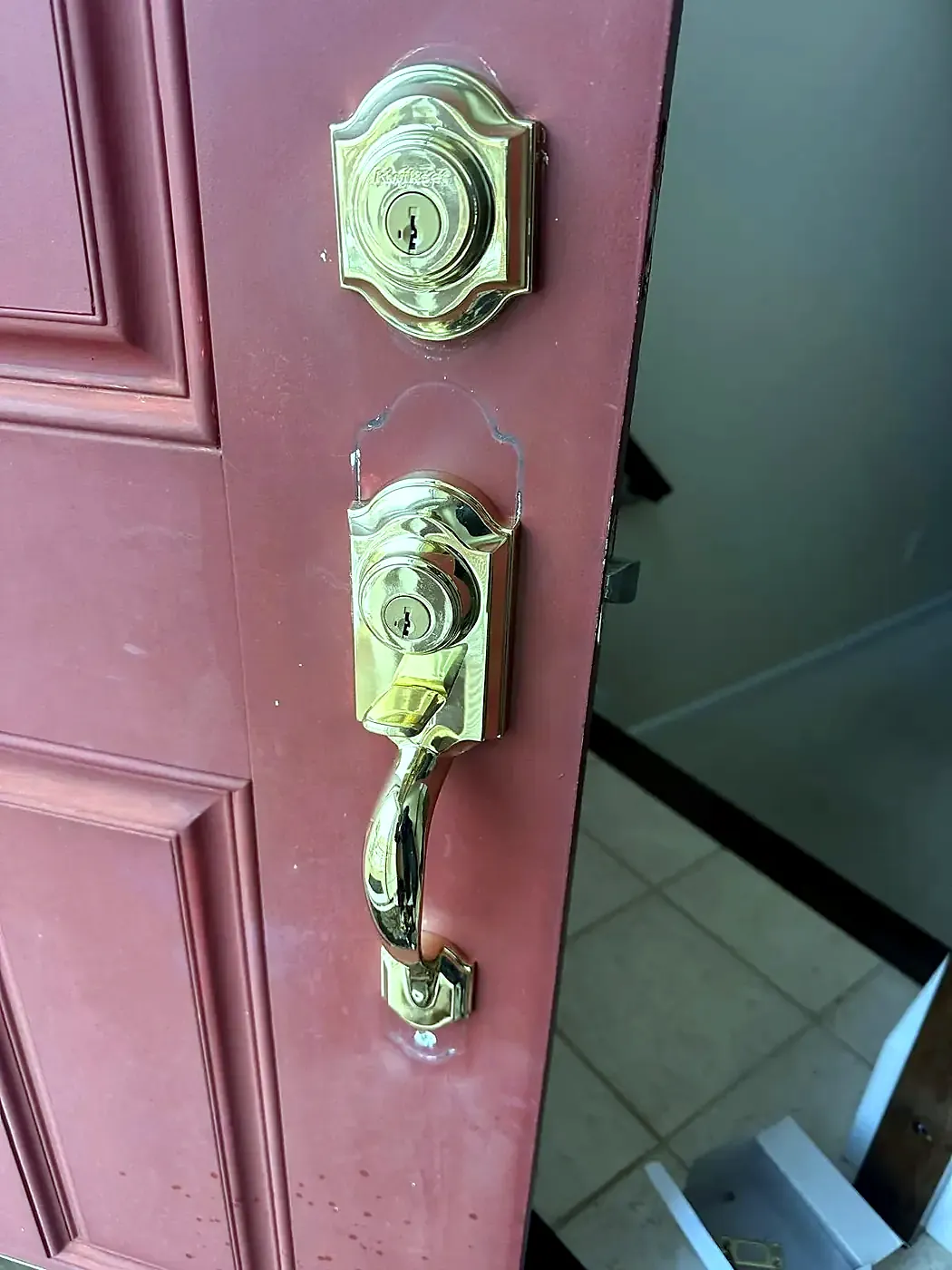 Close-up of a brass deadbolt and lever handleset on a red painted door edge