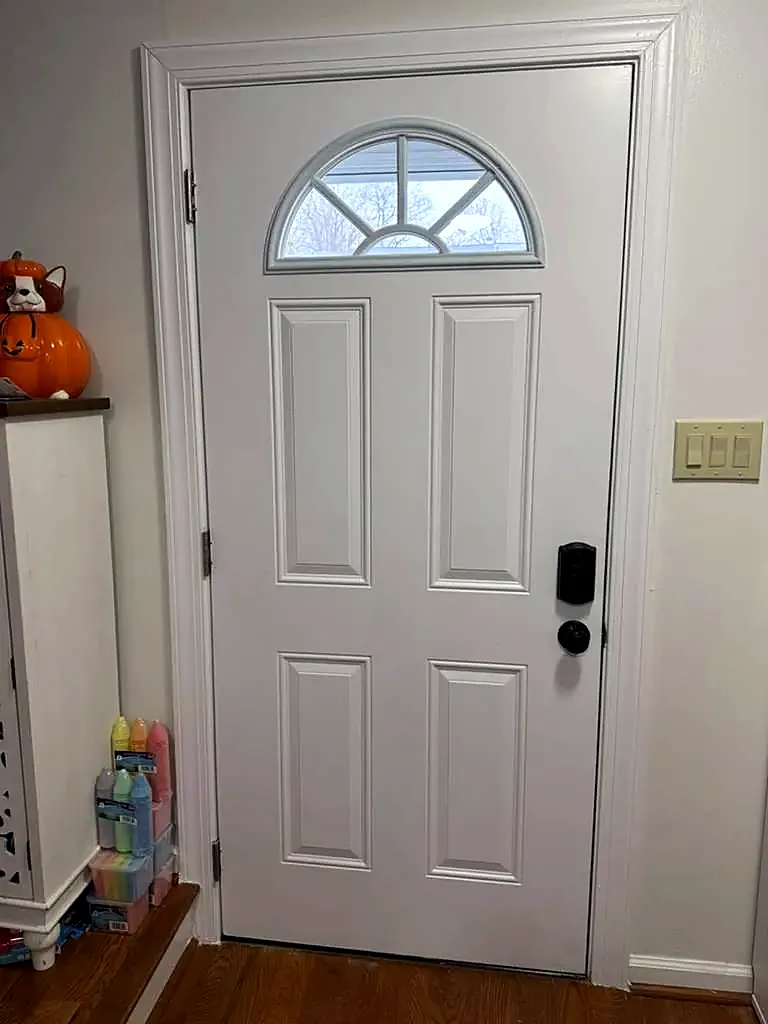 White six-panel front door with a fanlight window and black keypad lock, viewed from inside
