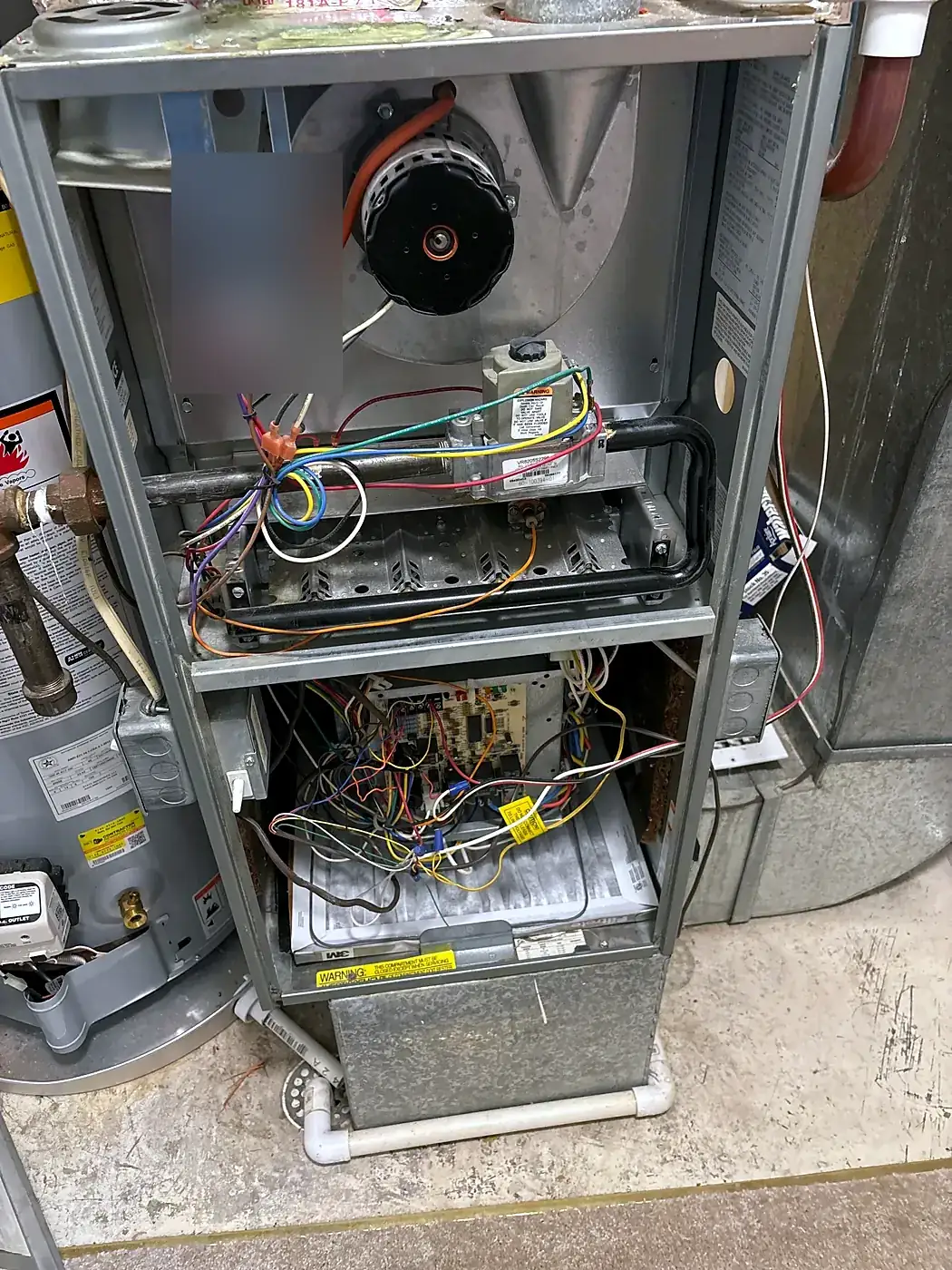Gas furnace with front panels removed showing the control board, wiring and inducer motor