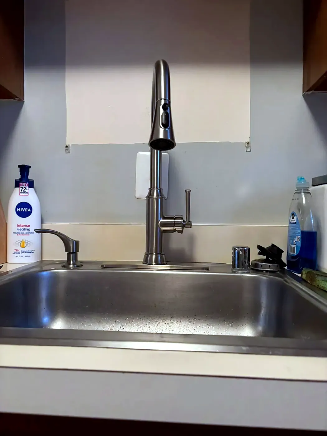 New brushed stainless pull-down kitchen faucet on a stainless sink with a white countertop