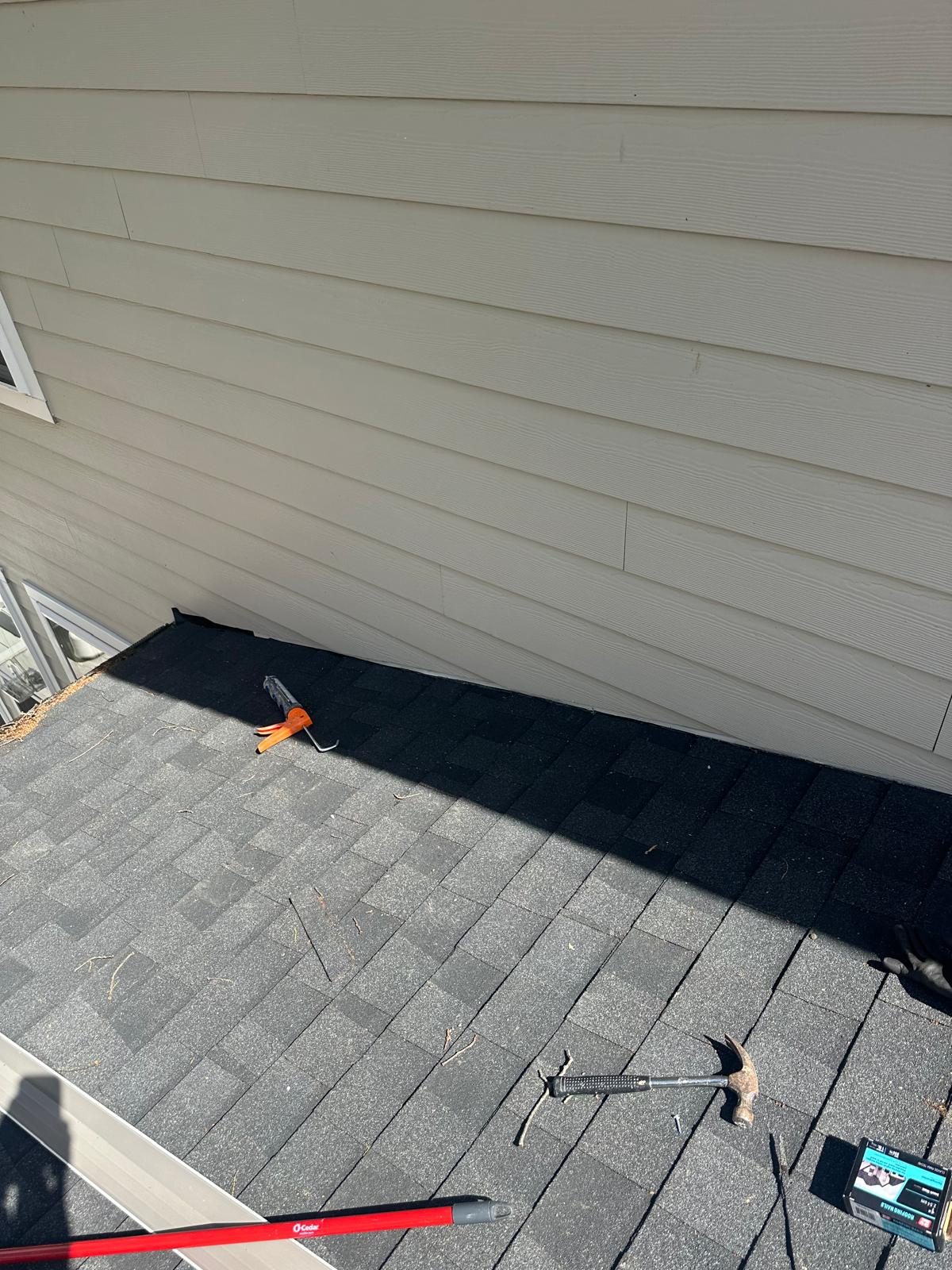 New flashing tucked behind the lower siding course where the wall meets the shingle roof