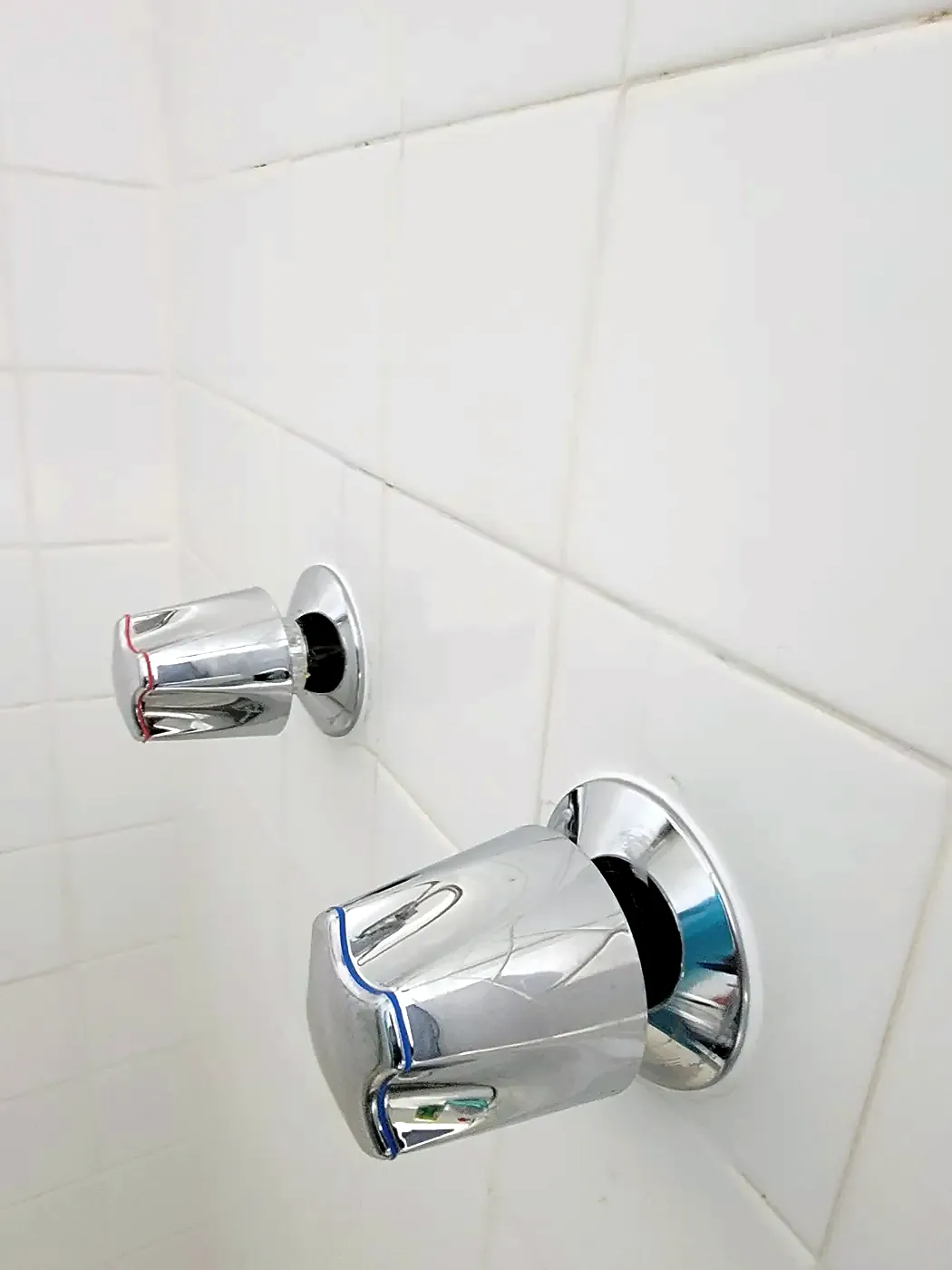 New chrome single-handle shower valve trim on a white tile wall