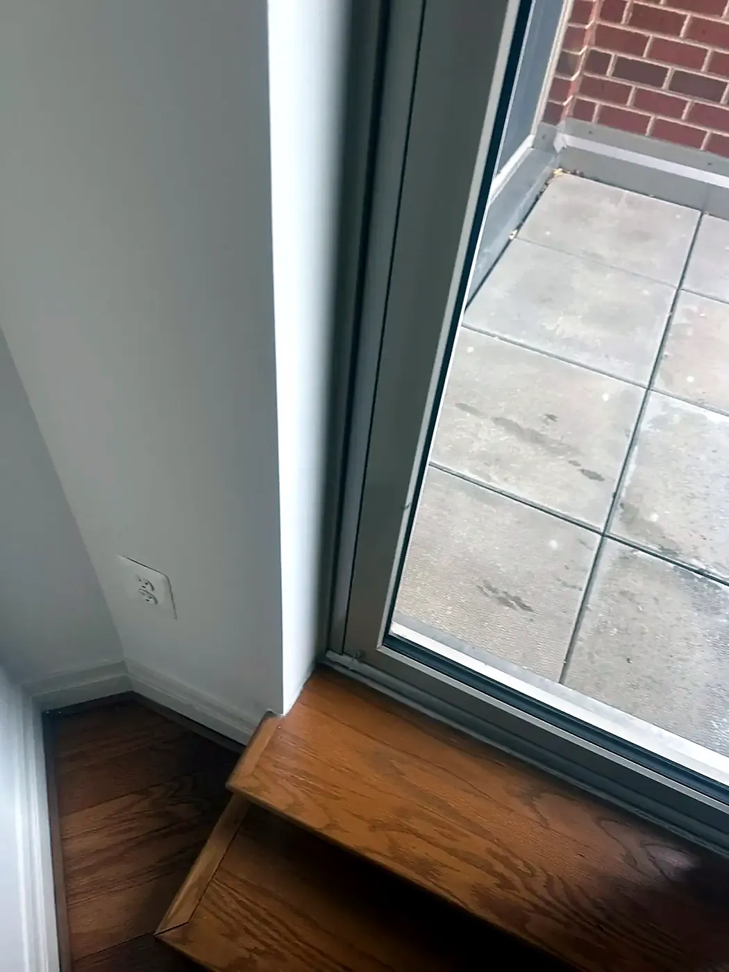 New sliding door track and threshold at a wood step, concrete patio outside