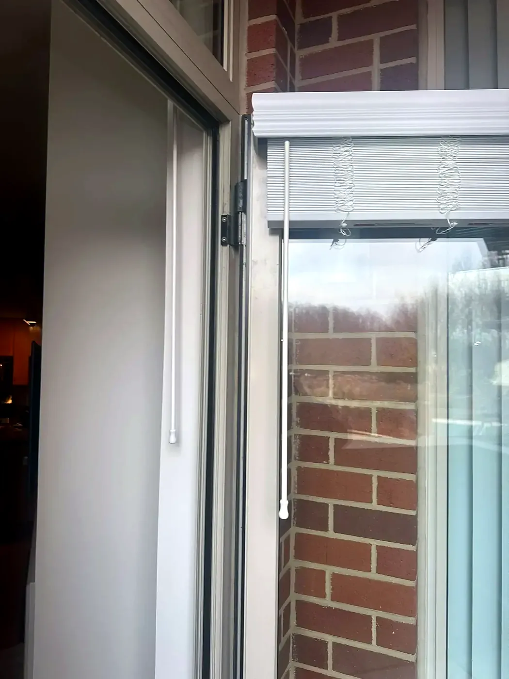 Open sliding glass door showing the lock-side frame and brick wall outside