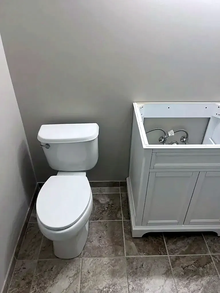 New white toilet and white vanity cabinet on a tile floor in a small bathroom