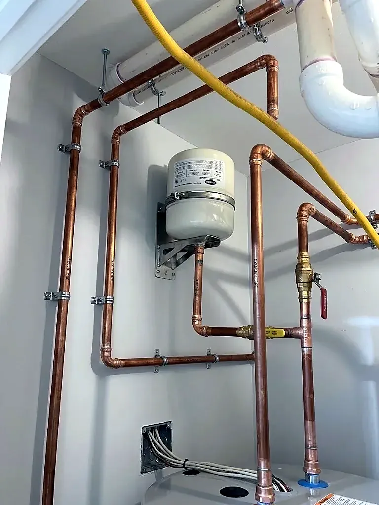 New copper water lines and an expansion tank mounted on a white wall, ball valve on the main