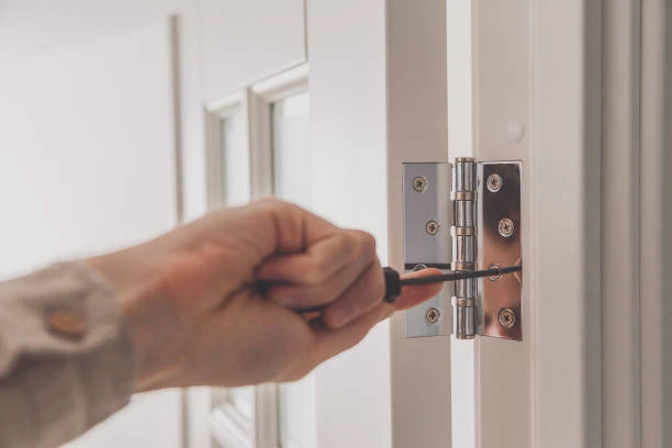 technician tightening a door hinge with a screwdriver during professional door hinge repair service.