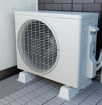 a sleek, white outdoor mini-split condenser unit professionally mounted on vibration-dampening risers for a high-efficiency ductless heating installation in mclean virginia.