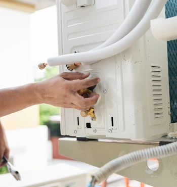 an hvac specialist performs a technical setup for a ductless heating installation in vienna va, using a wrench to calibrate refrigerant line connections and secure brass valves.
