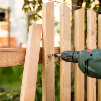 fence repair in arlington va with contractor securing wooden fence panels using a power drill