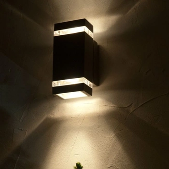 a modern black outdoor wall light fixture with a rectangular design casting up-and-down light on a textured wall, installed by professional flood light installers in reston va.