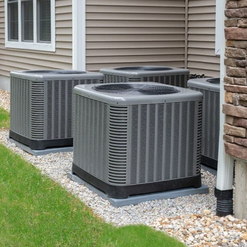 a row of four high-capacity grey outdoor condenser units professionally installed on level pads during a new heat pump installation in falls church va.