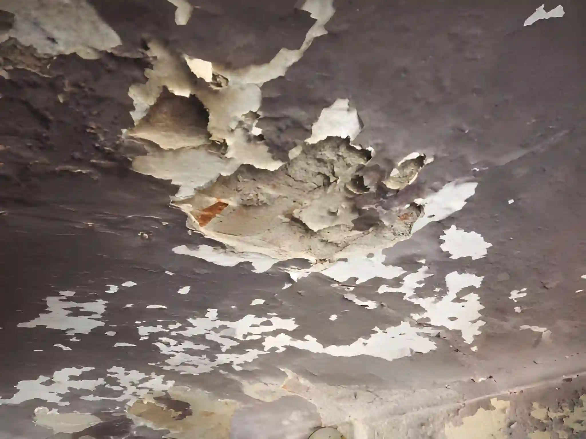severe ceiling damage from a roof leak with peeling paint requiring roof leak repair services in centreville va