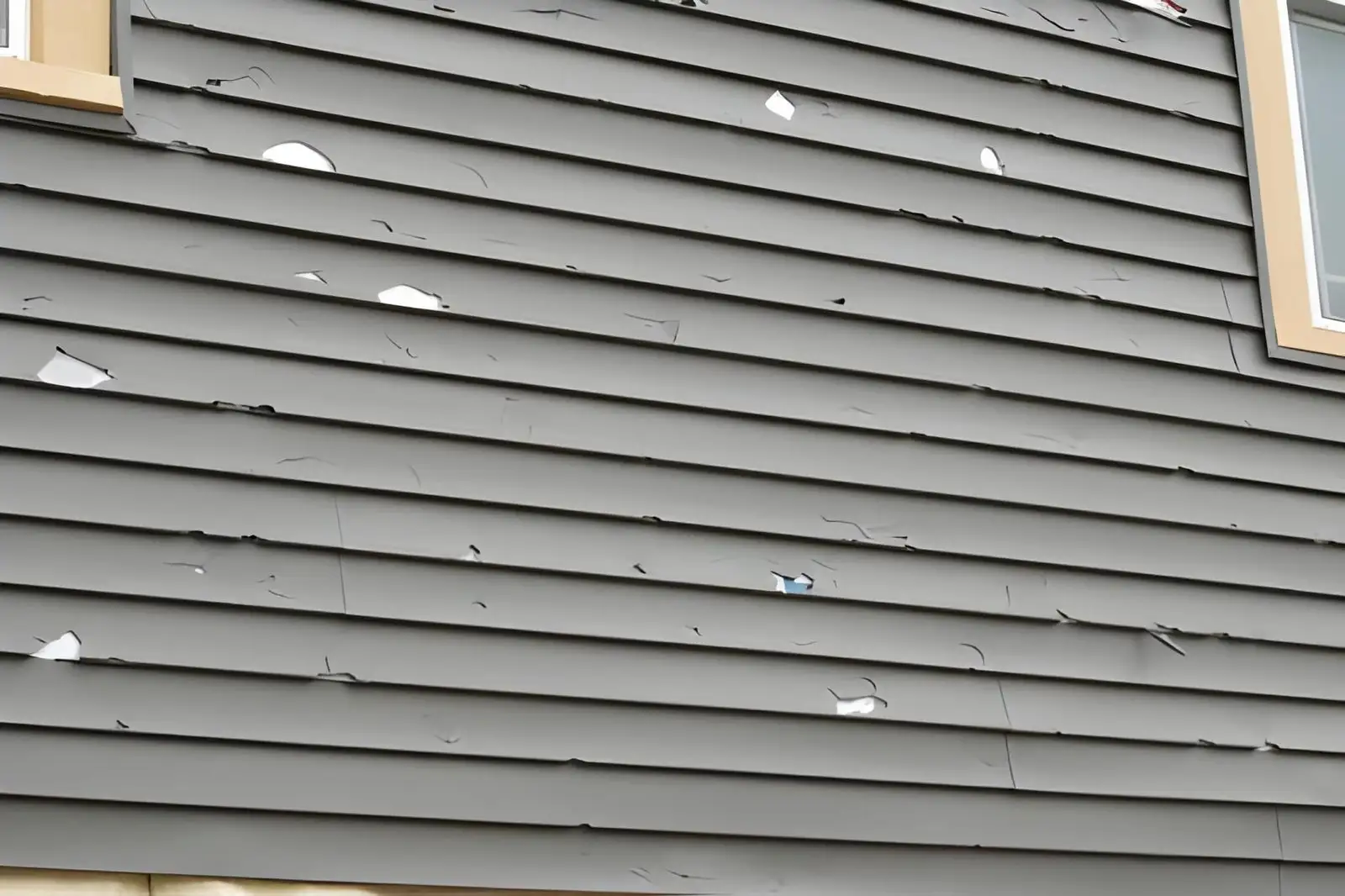 damaged vinyl house siding with cracks and peeling panels requiring professional siding repair.
