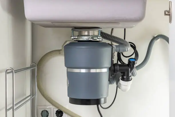 garbage disposal replacement under kitchen sink with new disposal unit connected to drain pipes