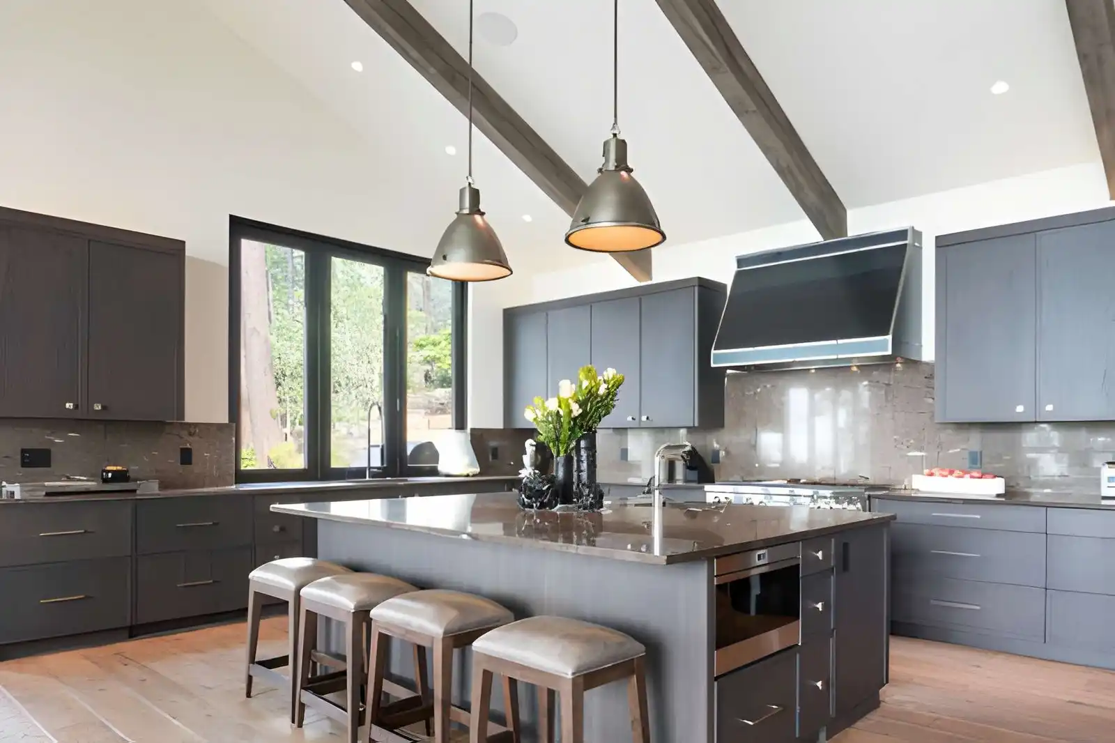 expert kitchen remodeling near northern va featuring charcoal gray shaker cabinetry, a large central island with a built-in microwave, vaulted ceilings with dark wood beams, and industrial pendant lighting.