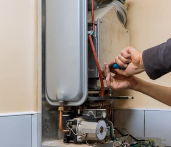 a technician using a hand tool to fix internal components and fuel lines during an emergency gas line repair in northern va on a residential tankless water heater system.