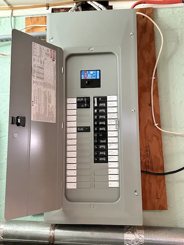 A newly installed Eaton 200 AMP electrical panel with its door open, showcasing neatly wired, code-compliant single-pole and double-pole breakers with detailed handwritten labels in Arlington, VA.