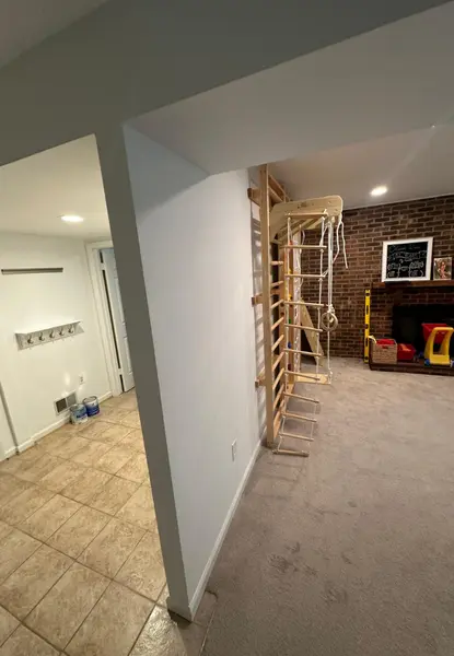 home additions in lorton va 4 internal threshold view of custom home additions in lorton, va, looking from a tiled entryway mudroom into a carpeted family recreation room featuring a custom wall-anchored wooden playground gym set and brick accents.