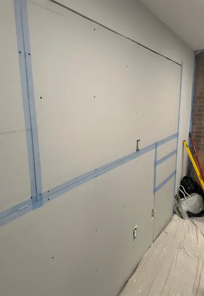 home additions in falls church va 2 in-progress interior drywall partition wall completed by certified home addition contractors in falls church, va, showing taped joint fields, smooth drywall mudding coats, and electrical boxes.