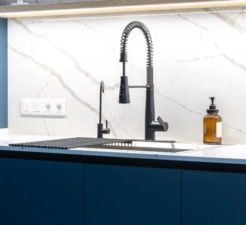 professional kitchen faucet repair in annandale , va, featuring a modern matte black industrial-style spring faucet installed on a white marble countertop with a luxury blue cabinet backdrop.